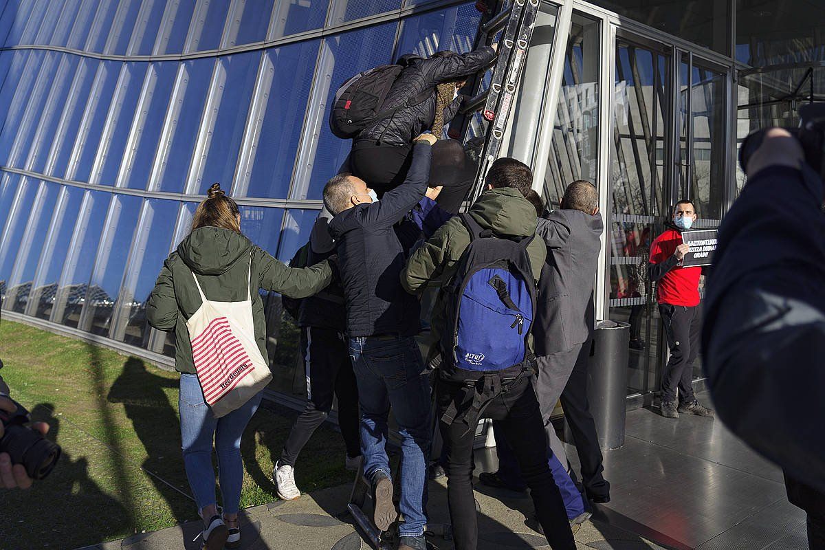 Lepoa Iberdrola dorrearen ateari lotu dio gazte batek. Beste batzuk atariko estalkira igotzen saiatu dira. ARITZ LOIOLA