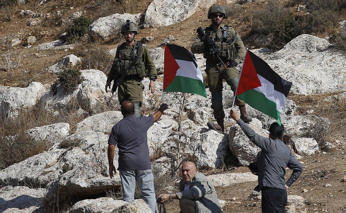 Bi palestinar Palestinako bandera eskuan hartuta, azaroan, Israelgo bi soldaduren aurrean, Nablusen. ALAA BADARNEH / EFE