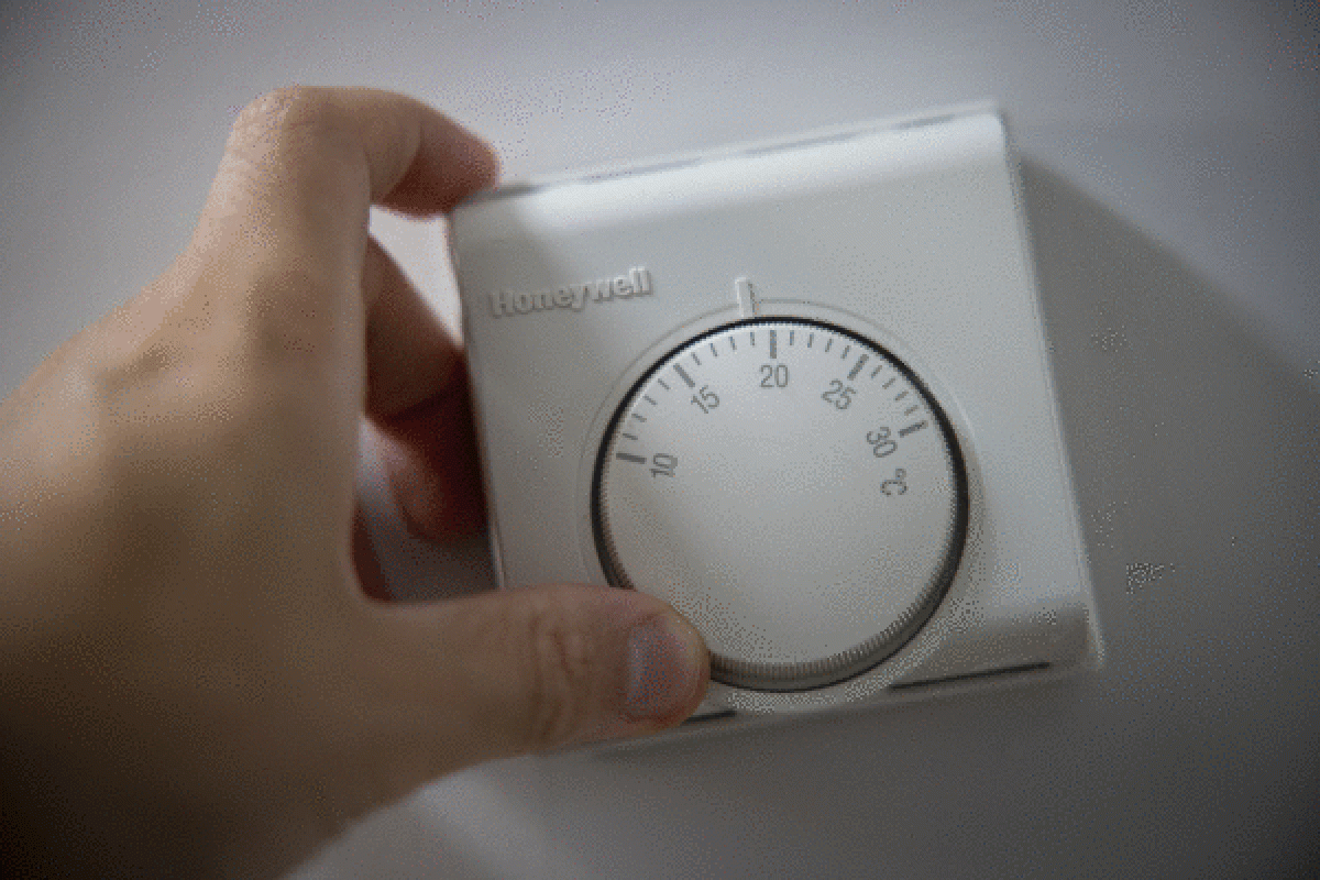 Pertsona bat termostato bateko graduak aldatzen. TOLGA AKMEN / EFE