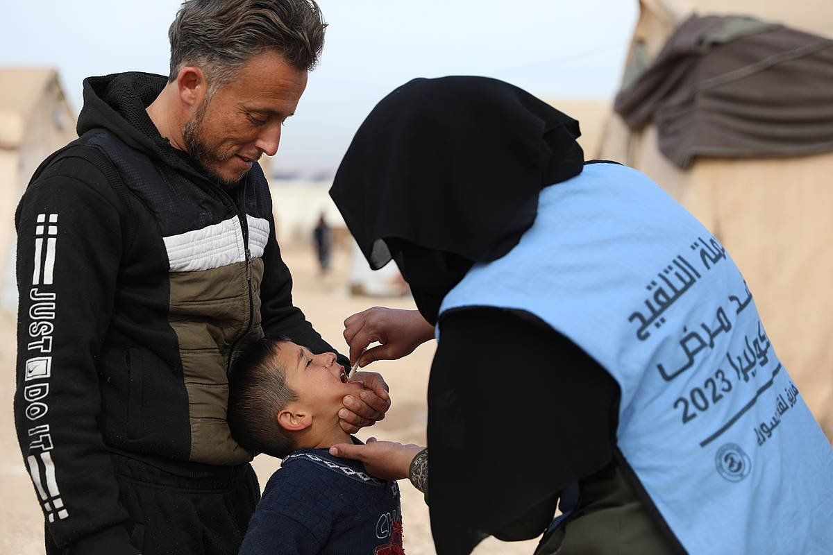 Osasun langile bat haur bati koleraren aurkako sendagaia ematen, Idliben, Siriako errefuxiatuen kanpaleku batean. YAHYA NEMAH / EFE