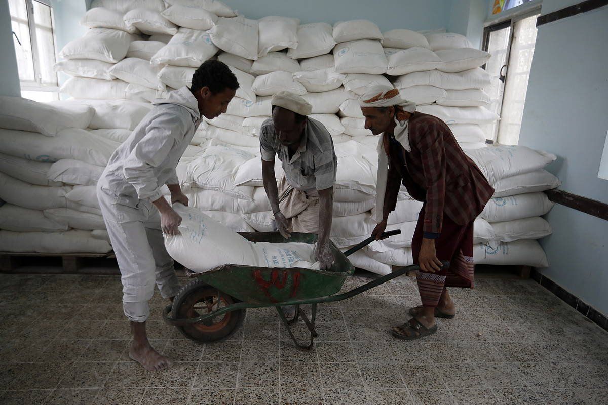 Yemengo hiru herritar, elikagai zakuak banatzeko lanean, maiatzaren 15ean, Munduko Elikadura Programak Sana hiriburuan duen egoitzan.. YAHYA ARHAB / EFE