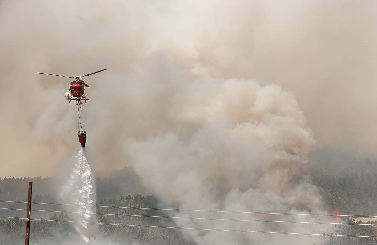 Helikoptero bat ura hartuta sutea itzaltze lanetan. JESUS DIGES / EFE