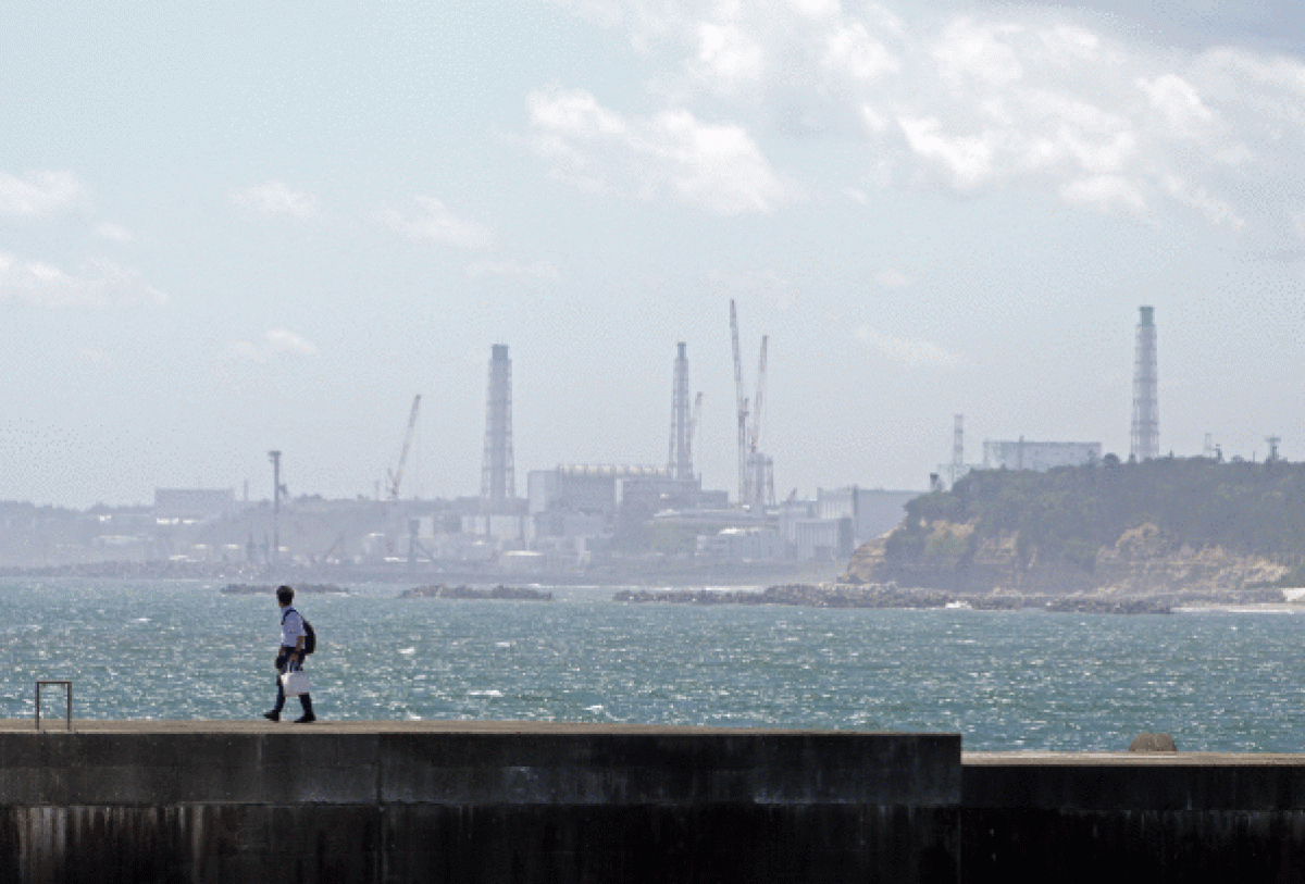 Gizon bat oinez Fukushimako ur kutsatuak isuriko dituzten Ukedoko portuaren alboan, Namien, gaur. FRANCK ROBICHON / EFE