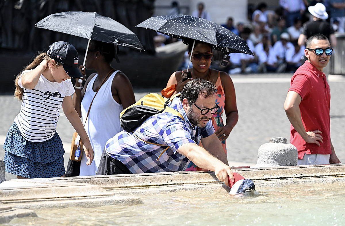 Zenbait turista, iturriaren ondoan, bero sapa betean, uztail amaieran, Vatikano Hirian. CLAUDIO PERI / EFE