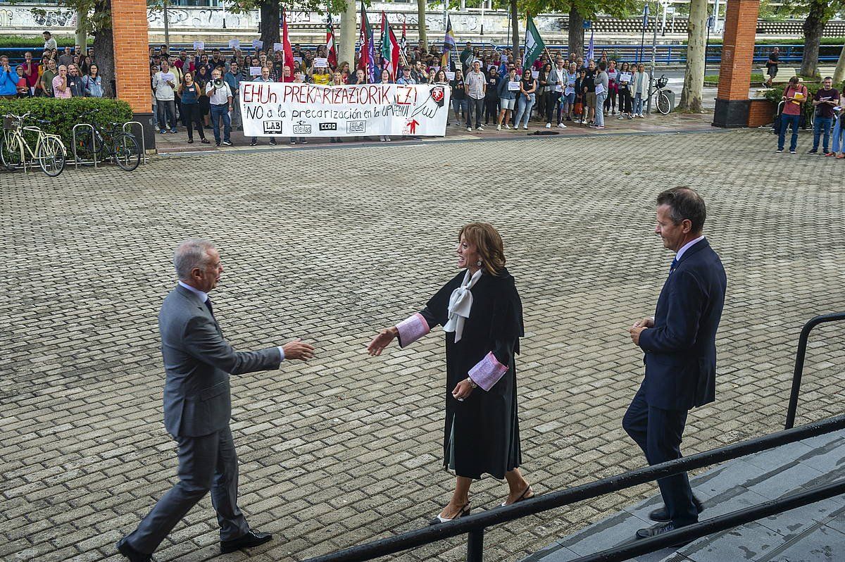 Iñigo Urkullu eta Eva Ferreira, gaur goizean, ekitaldia hasi aurretik elkar agurtzen. Atzean, irakasleak protestan. JAIZKI FONTANEDA/ FOKU