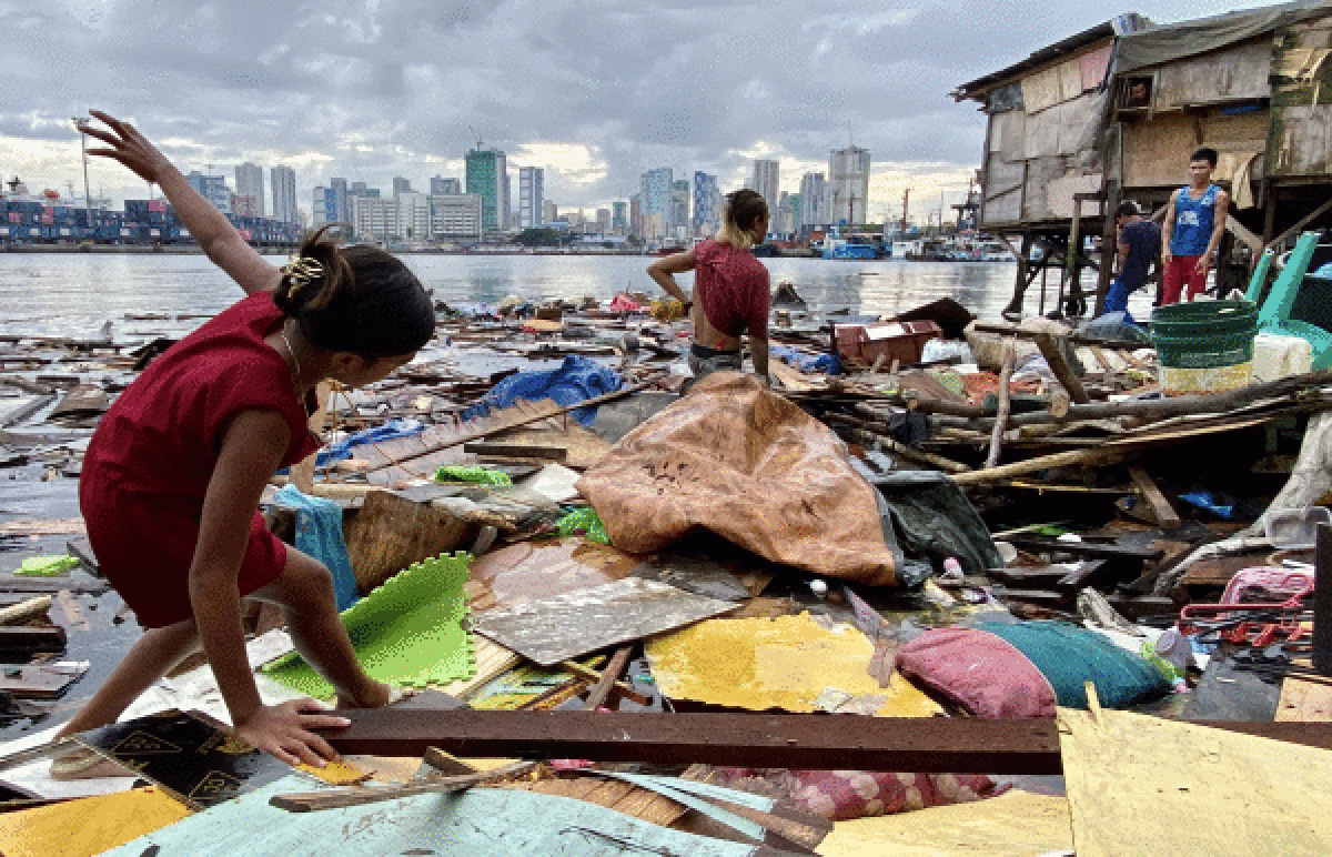 Zenbait haur tifoi batek suntsitutako etxe baten zatiak jasotzen, Manilan, Filipinetan, astelehenean. FRANCIS R. MALASIG /EFE