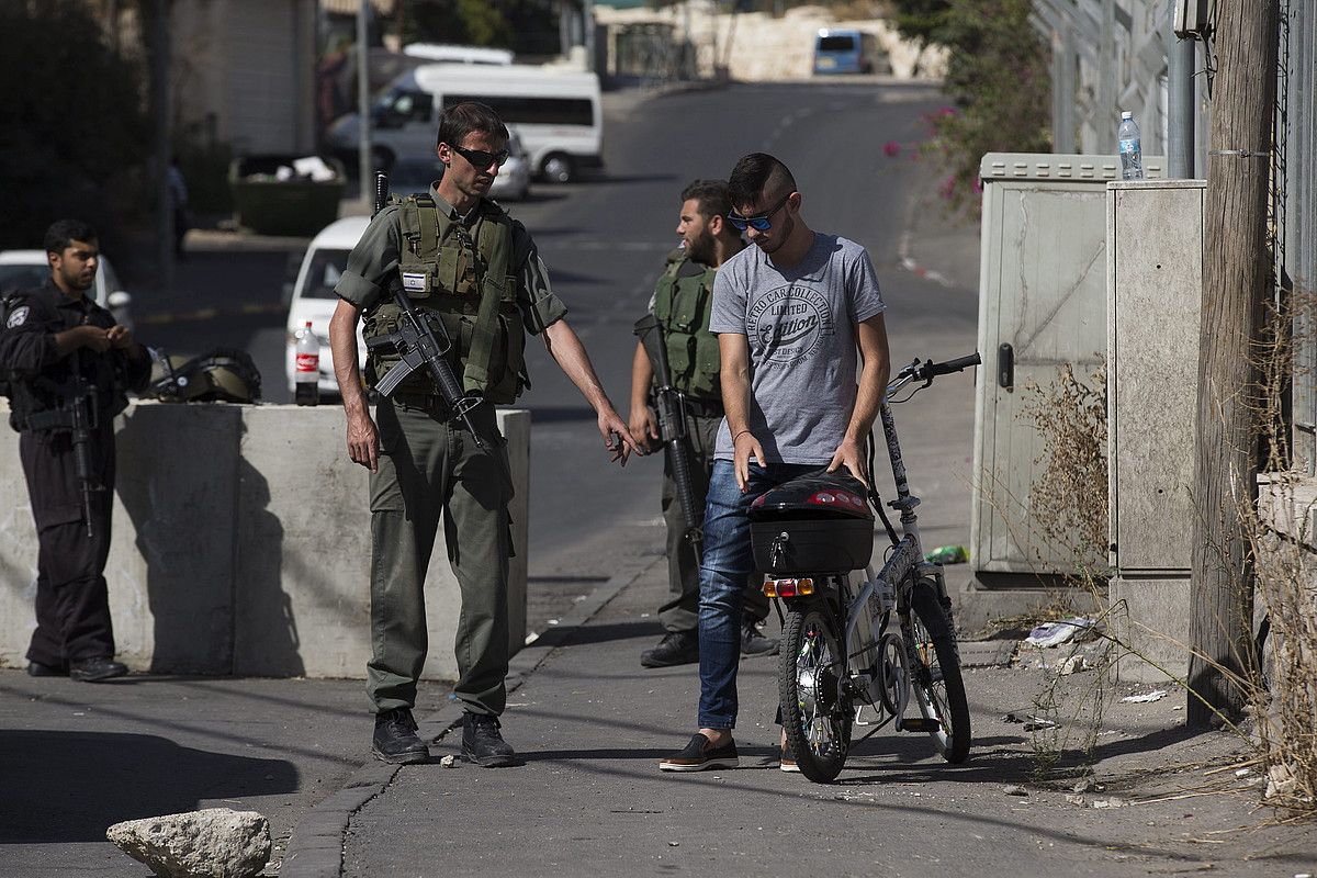 Polizia israeldarrak, Jerusalemgo Al-Amud auzoko sarreran ezarritako kontrolean, atzo, palestinar bat miatzen. ATEF SAFADI / EFE.