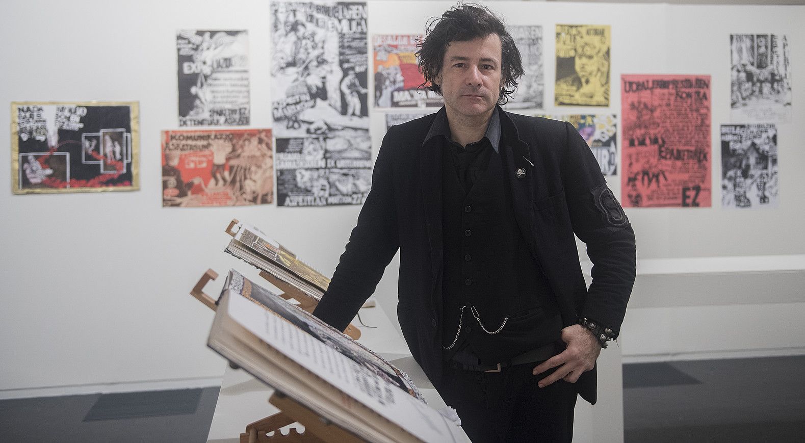 Detritus, berak sortutako artista koadernoak alboan eta kartelak atzean zituela, atzo, Donostian. ANDONI CANELLADA / ARP.