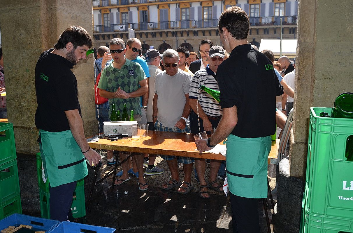 Sagardogileak, mahaira bildutako sagardozaleei zerbitzatzen. ESTITXU ZABALA / IRUTXULOKO HITZA. Sagardogileak, mahaira bildutako sagardozaleei zerbitzatzen. ESTITXU ZABALA / IRUTXULOKO HITZA.