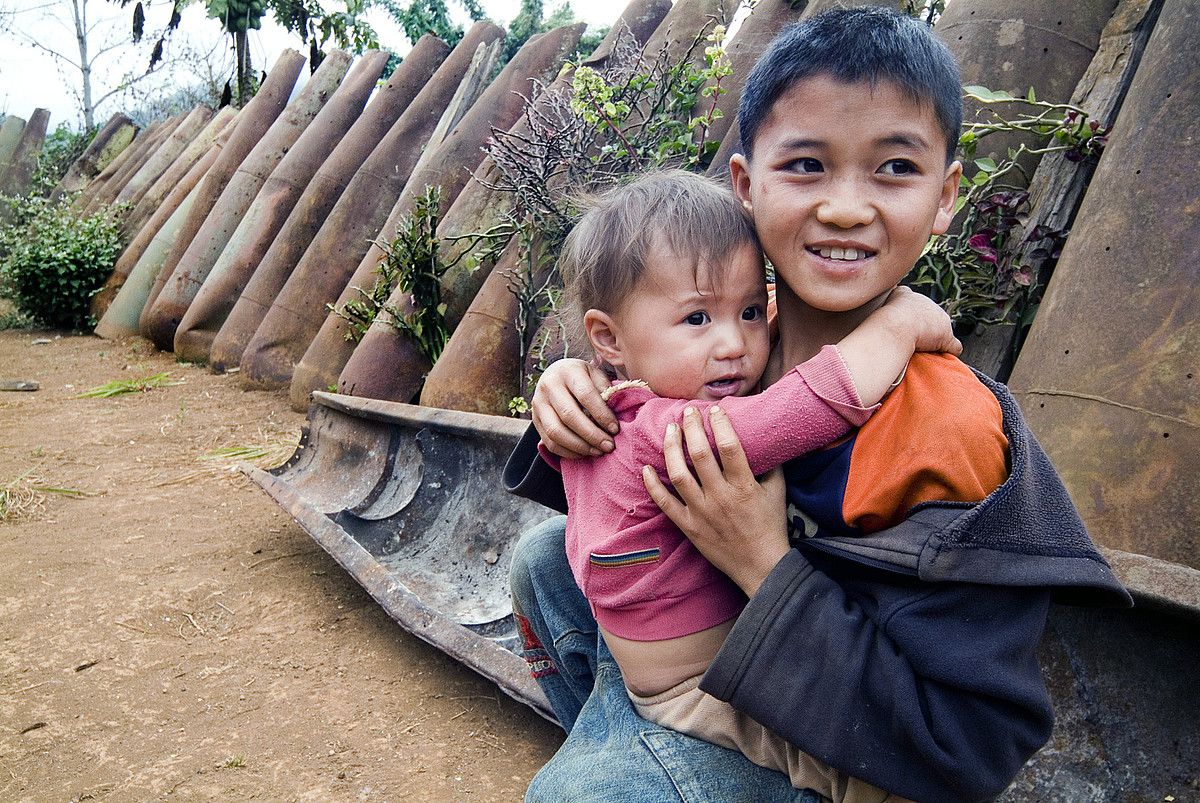 Bi haur jolasean, 500 kiloko bonben estalkien artean, Laoseko Xien Khuang probintzian. Txatarra gisa birziklatzen dituzte estalkiak. ZIGOR ALDAMA.