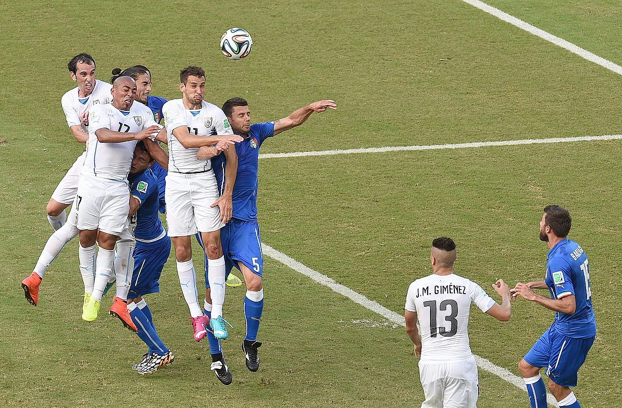 Italiako eta Uruguaiko zazpi jokalari, lehian, baloia jo nahian. Diego Godinek, eskuinetik lehenak, eman zion buruz, eta partidako gol bakarra sartu. VASSIL DONEV / EFE.