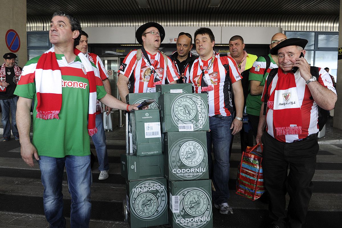 Athleticeko zale batzuk xanpaina botilez betetako kaxekin, atzo, Bukaresteko aireportura iritsi berritan. JON ESKUDERO. Athleticeko zale batzuk xanpaina botilez betetako kaxekin, atzo, Bukaresteko aireportura iritsi berritan. JON ESKUDERO.