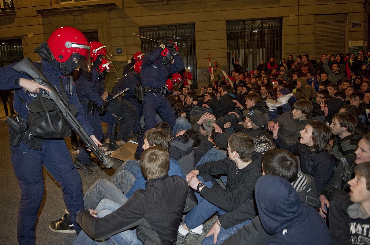 Ertzain bat, pilota botatzeko armarekin, gazte baten alboan. RAUL BOGAJO / ARP.