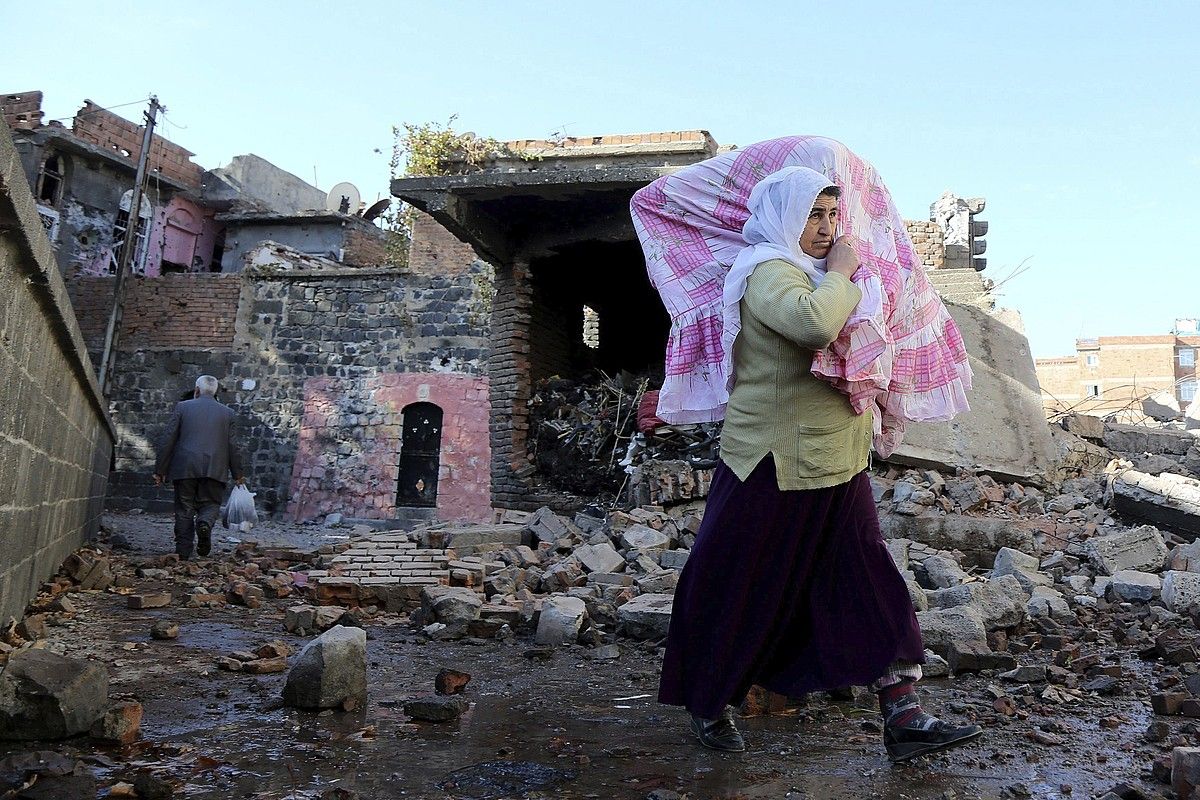 Diyarbakirko herritar bat, etxetik ihes egiten, joan den abenduan, Turkiako armadaren erasoaren ostean. EFE. Diyarbakirko herritar bat, etxetik ihes egiten, joan den abenduan, Turkiako armadaren erasoaren ostean. EFE.