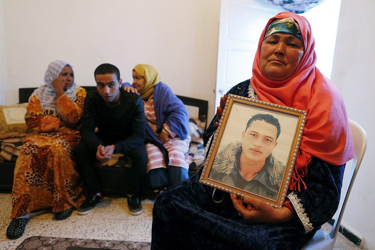 Anis Amriren ama Nour Huda, semearen argazkia eskuan duela, etxean; atzean, seme-alabak. MOHAMED MESSARA / EFE. Anis Amriren ama Nour Huda, semearen argazkia eskuan duela, etxean; atzean, seme-alabak. MOHAMED MESSARA / EFE.