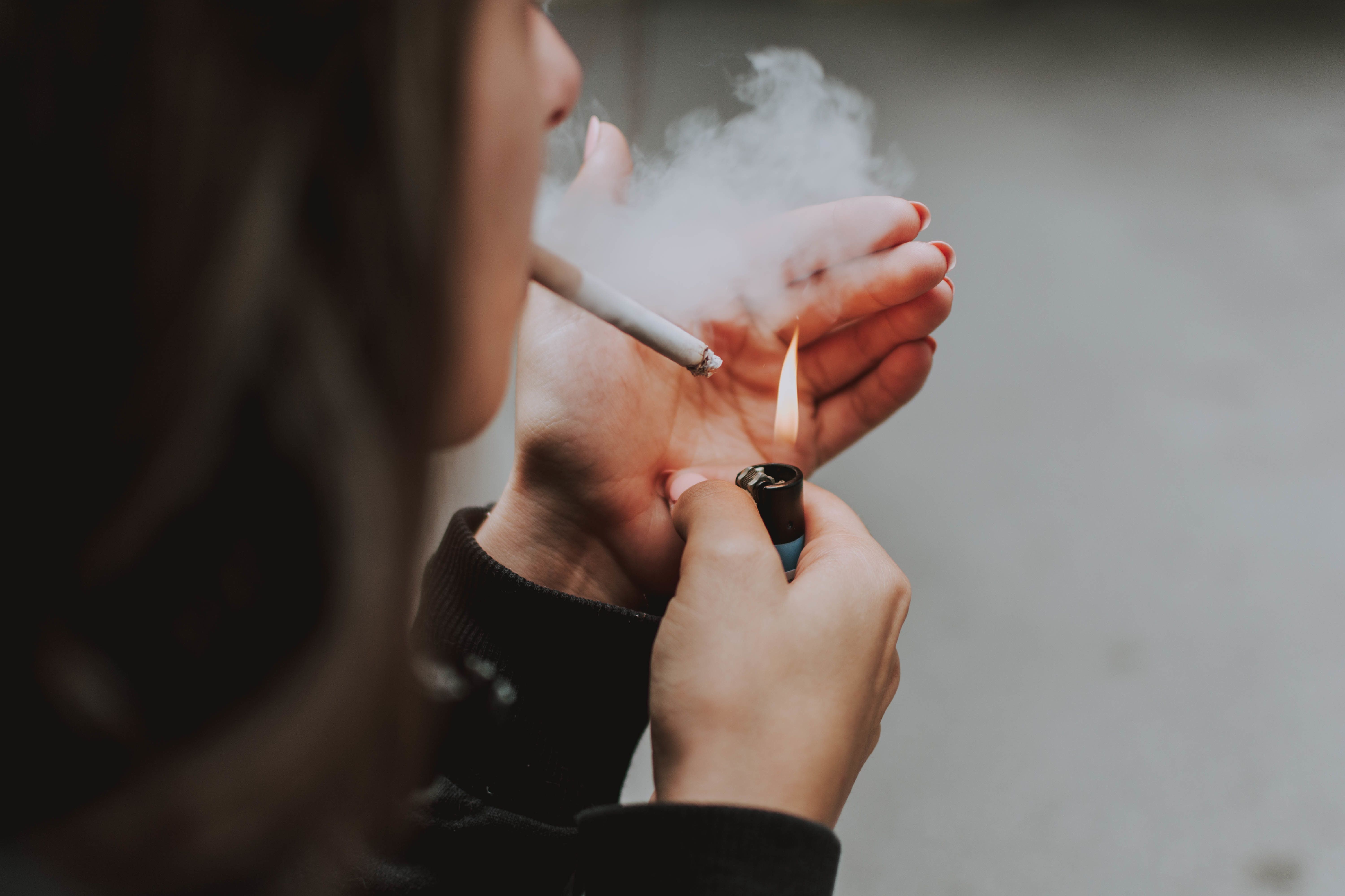 Selective closeup shot of a female lighting up a cigarette with a lighter