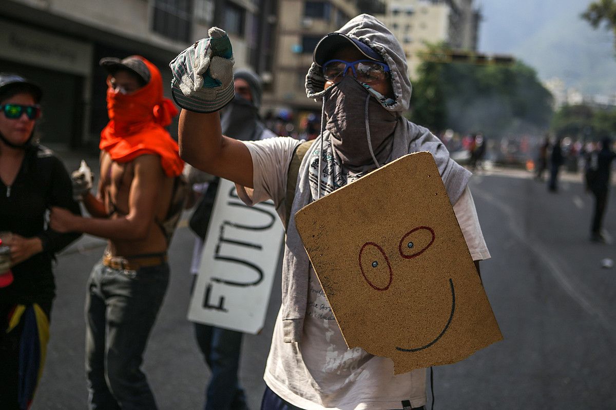 Oposizioko jarraitzaileak Poliziari aurre egiten Caracasen, herenegun. 20 urteko gazte bat hil zen istiluen eremuan. CRISTIAN HERNANDEZ / EFE.