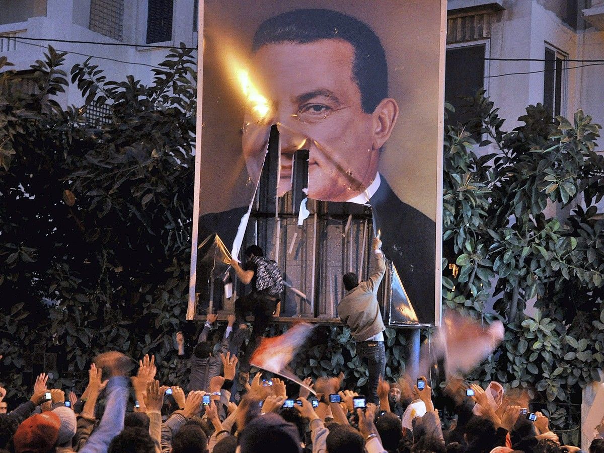Herritarrak Hosni Mubaraken irudi bat hondatzen, 2011ko urtarrilaren 25ean, Alejandrian. AHMED YOUSSEF / EFE.