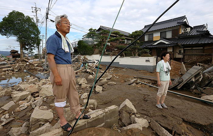 Bi japoniar lurrez estalitako errepidean eta hondatutako eraikinen artean oinez, Okayama eskualdeko Kurashiki hirian. JIJI PRESS, EFE