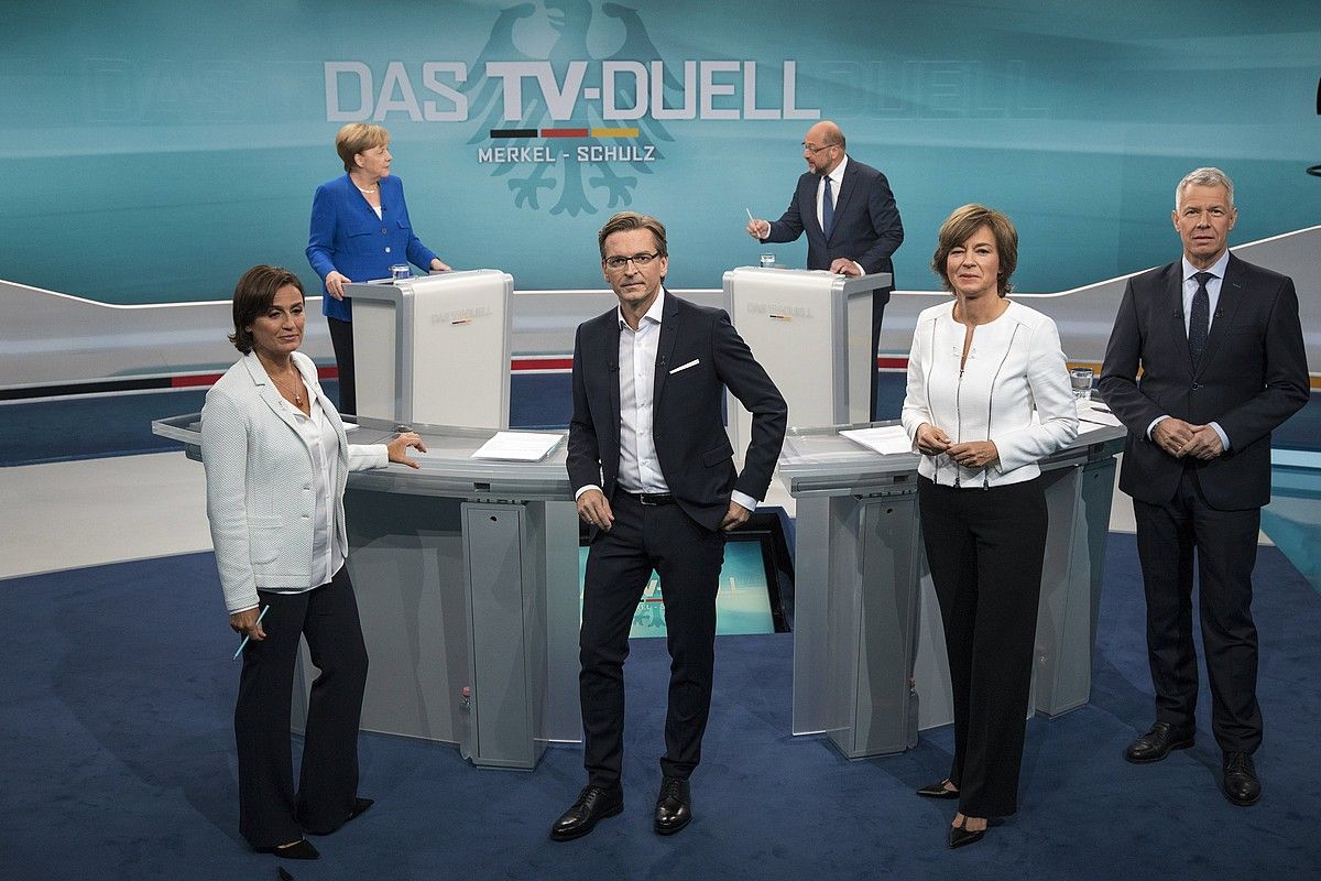Angela Merkel CDU/CSUko hautagaia eta Martin Schulz SPDkoa atzean ageri dira, solasean. Aurrealdean, kritikak pairatu dituzten moderatzaileak. HERBY SACHS / EFE.
