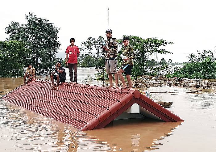 Herritar multzo bat laguntza iritsi zain, etxe bateko teilatuaren gainean, Attapeu ondoko herri batean. ABC LAOS NEWS, EFE