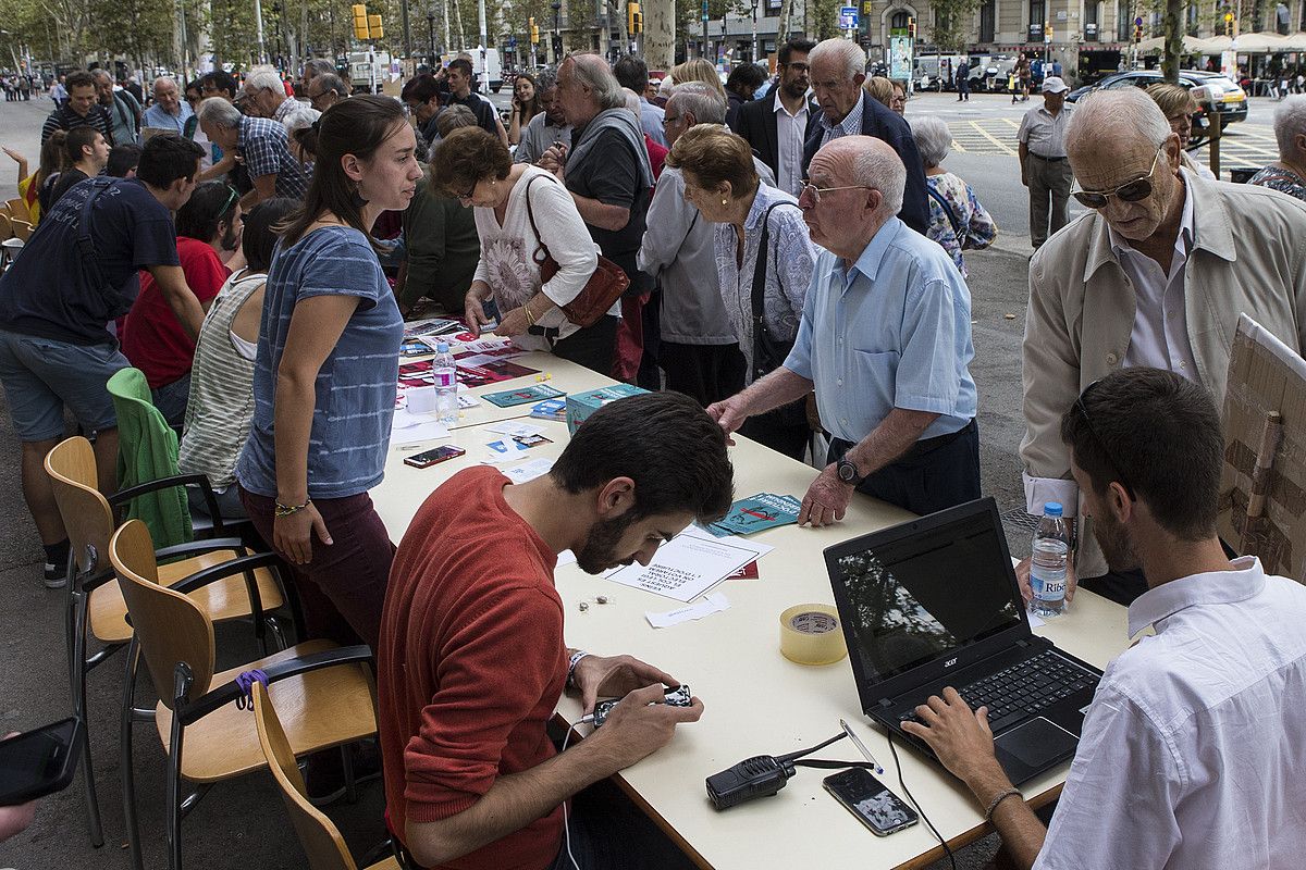 Ikasleak Bartzelonako Unibertsitateko atarian, herritarrei jakinarazteko zein tokitan bozkatu dezaketen datorren igandeko erreferendumean. QUIQUE GARCIA / EFE.