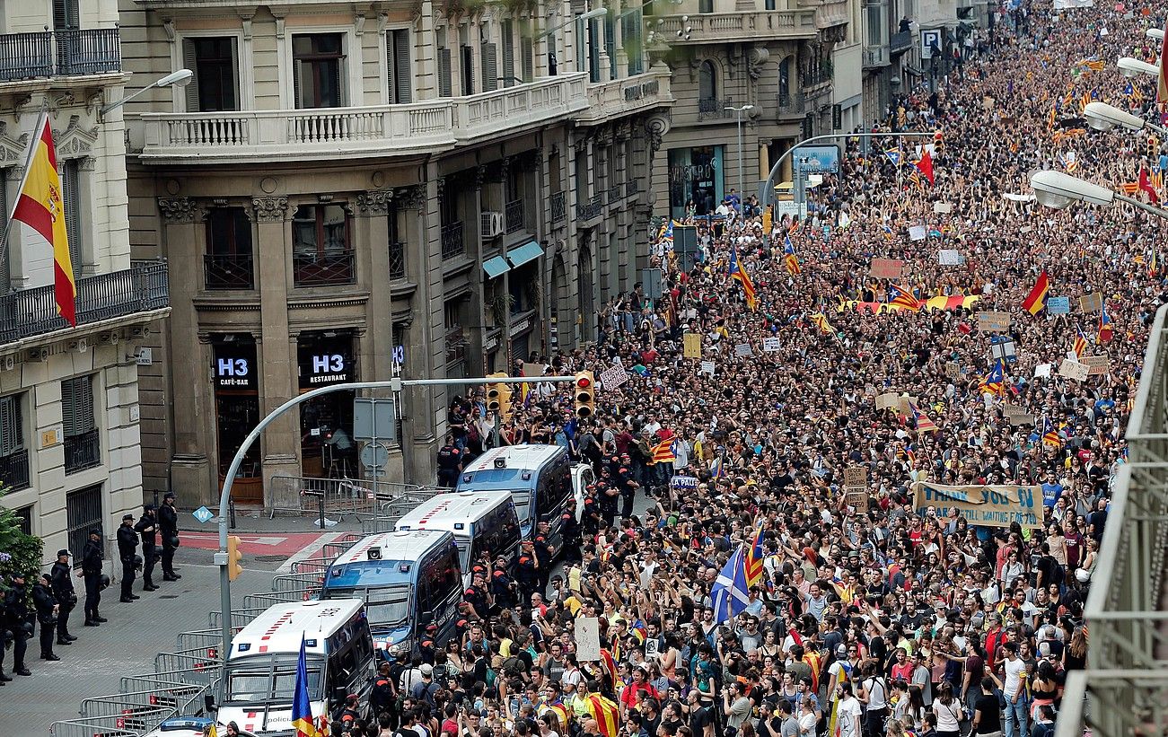 Hainbat manifestari Espainiako Poliziaren egoitza baten aurretik igarotzen, atzo, Bartzelonan, igandeko errepresioa salatzeko lanuztean. JUAN CARLOS CÁRDELNAS / EFE.