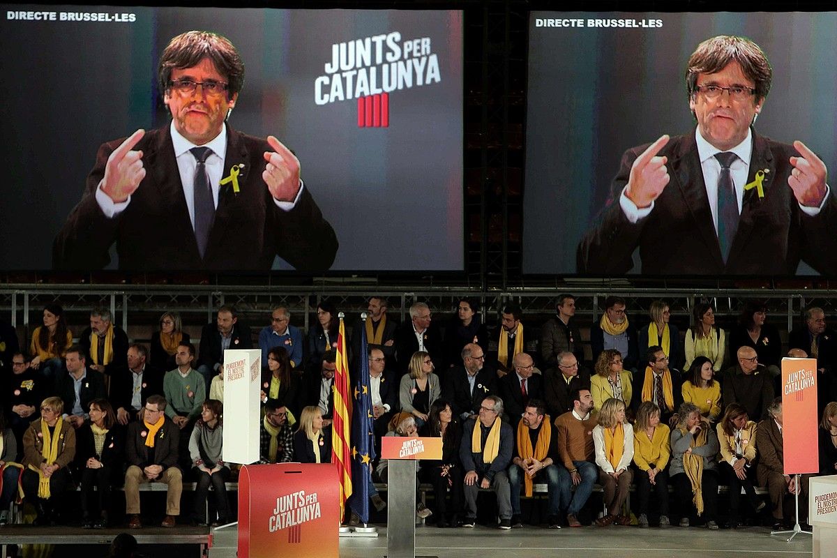 Carles Puigdemont bideo konferentziaz hitz egiten, Junts Per Catalunyak atzo egindako ekitaldian. TONI ALBIR / EFE. Carles Puigdemont bideo konferentziaz hitz egiten, Junts Per Catalunyak atzo egindako ekitaldian. TONI ALBIR / EFE.