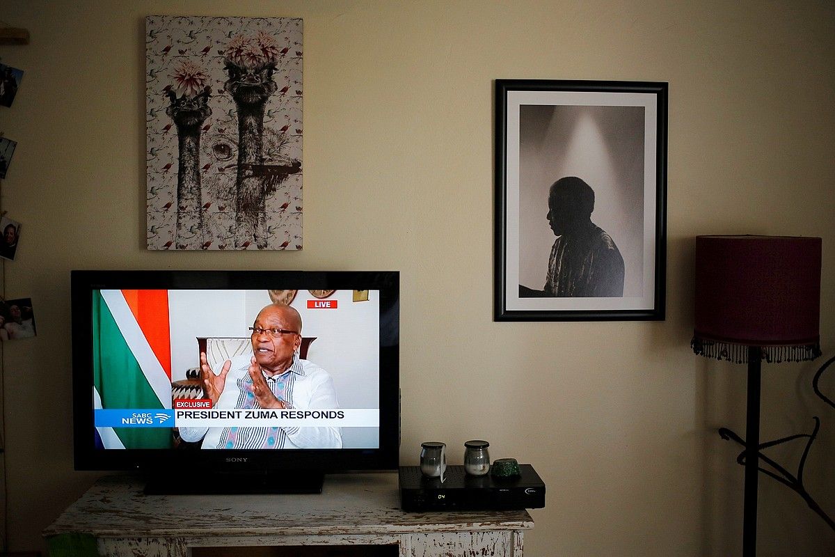 Pretoriako etxe batean ateratako irudi bat; Jacob Zuma, telebistako pantailan, eta Nelson Mandela hormako argazki batean. KIM LUDBROOK / EFE. Pretoriako etxe batean ateratako irudi bat; Jacob Zuma, telebistako pantailan, eta Nelson Mandela hormako argazki batean. KIM LUDBROOK / EFE.