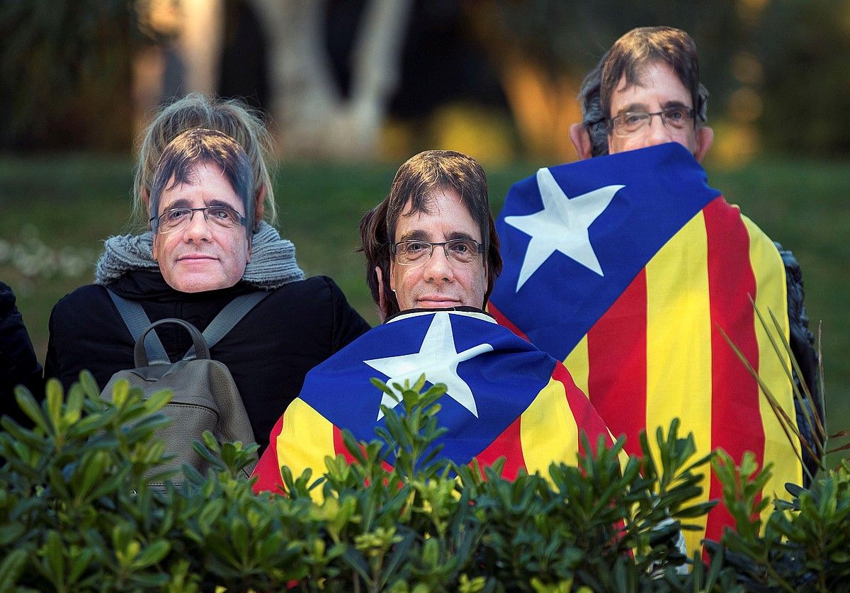 Hiru pertsona Puigdemonten aurpegiaren maskarekin, urtarrilaren 30ean parlamentuaren kanpoaldean. E.FONTCUBERTA / EFE.
