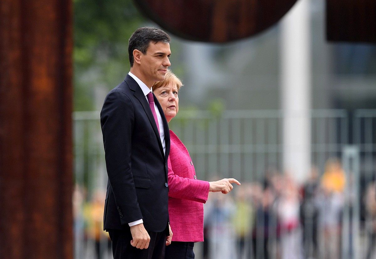 Pedro Sanchez eta Angela Merkel gobernuburuak, atzo, Alemaniako Kantzilertzaren jardinetan dagoen Eduardo Txillida eskulturaren ondoan. CLEMENS BILAN / EFE.
