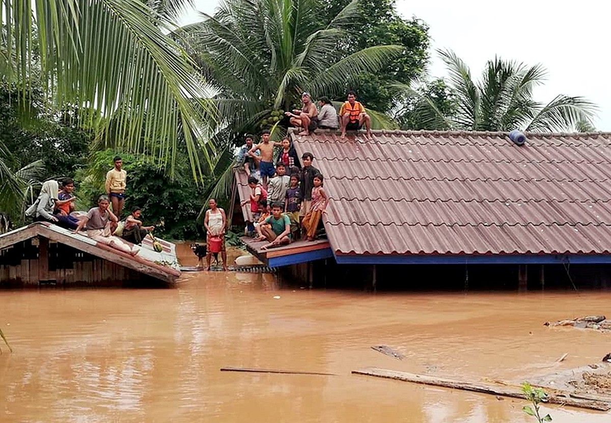 Hainbat pertsona teilatu gainean babes bila, atzo, Laosen. ABC LAOS NEWS /EFE.