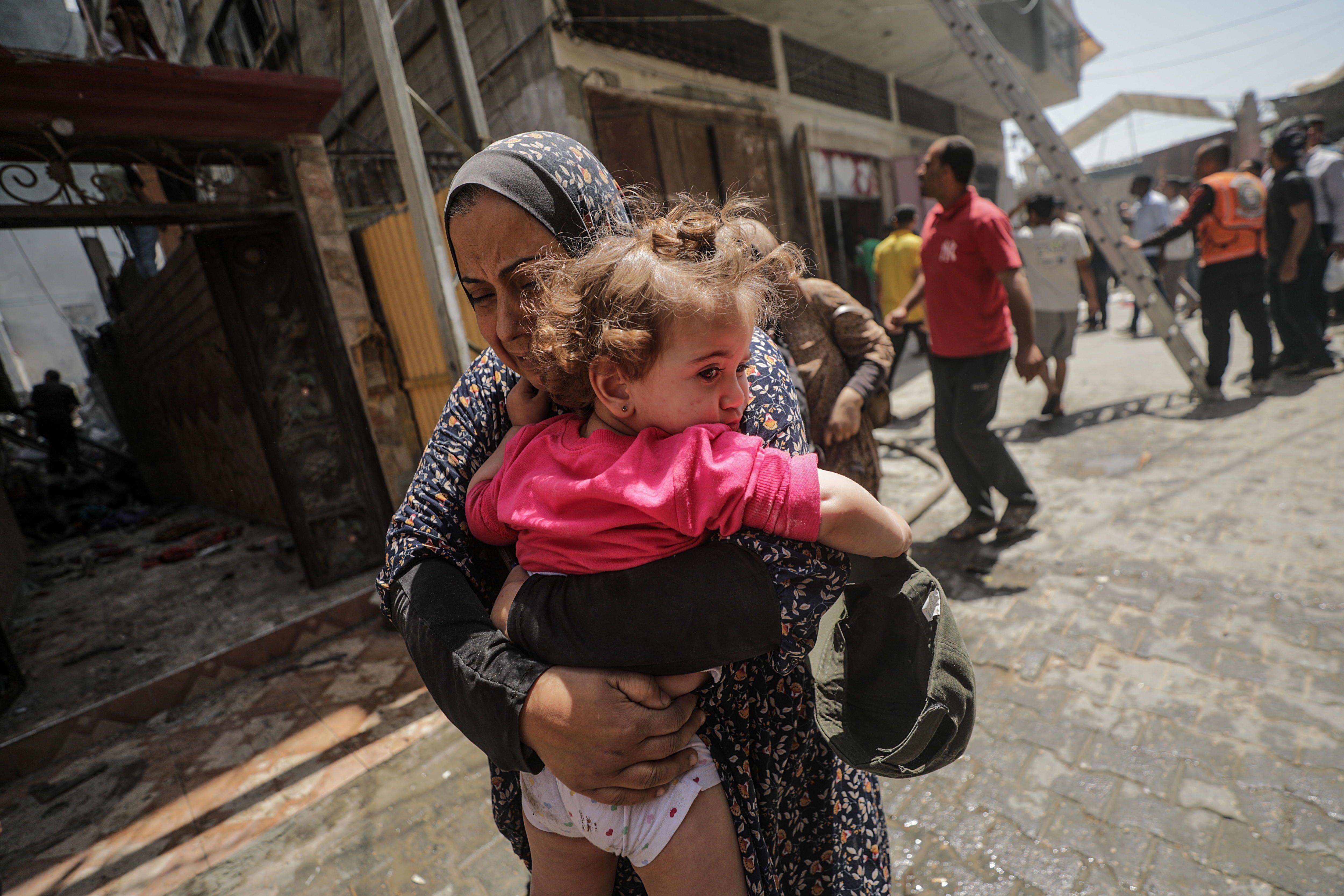 Emakume palestinar bat, haur bat besoetan duela, Israelek Al Nuseirat errefuxiatu esparruari eraso egin ostean, atzo, Gazan. MOHAMED SABER / EFE