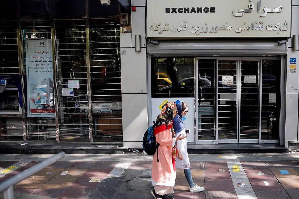 Bi neska moneta aldatzeko bulego baten aurrean, Teheranen. Riala asko debaluatu da azken hilabeteotan. ABEDIN TAHERKENAREH / EFE.