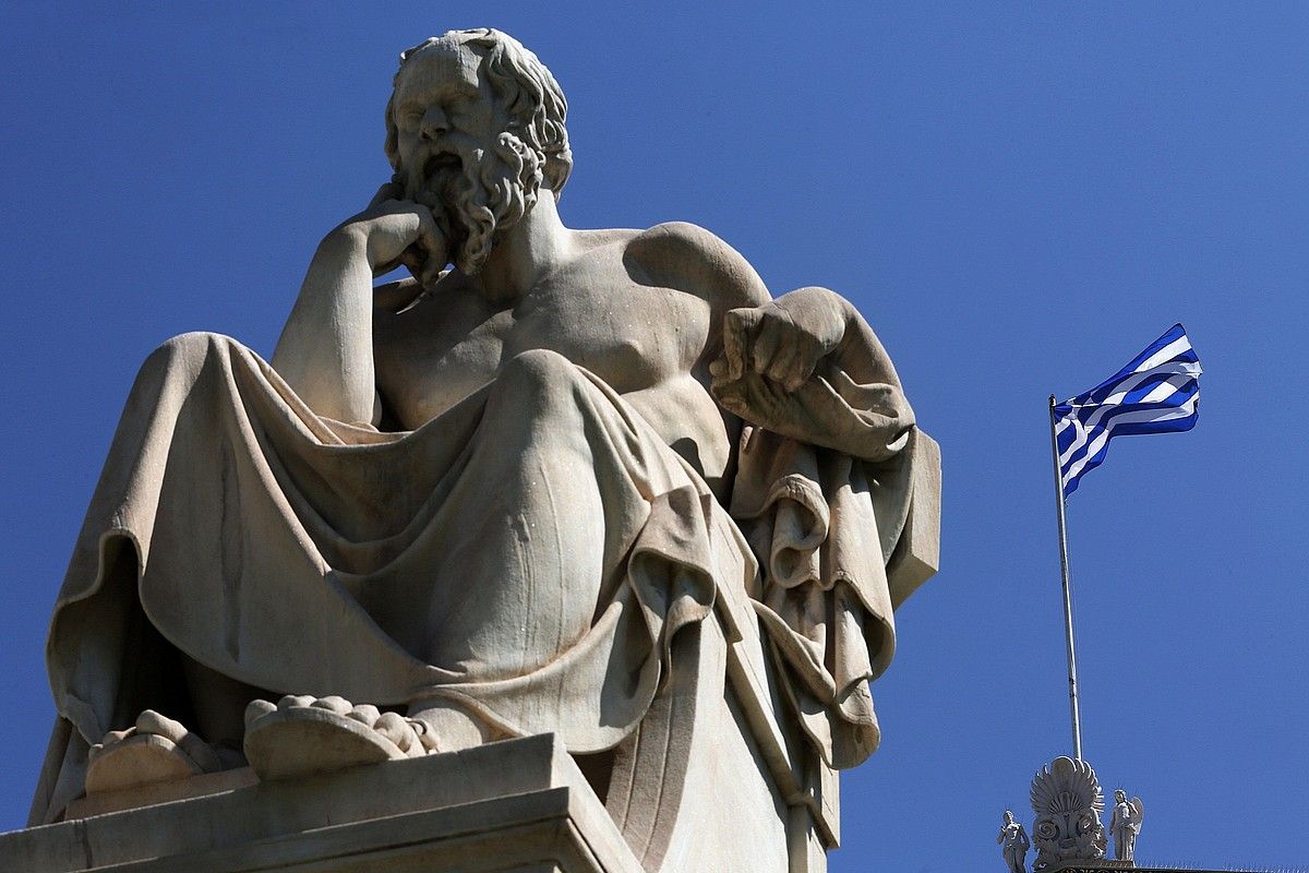 Greziako bandera bat, atzo, Atenasen, Sokrates filosofoaren estatua baten atzean. SIMELA PANTZARTZI / EFE.
