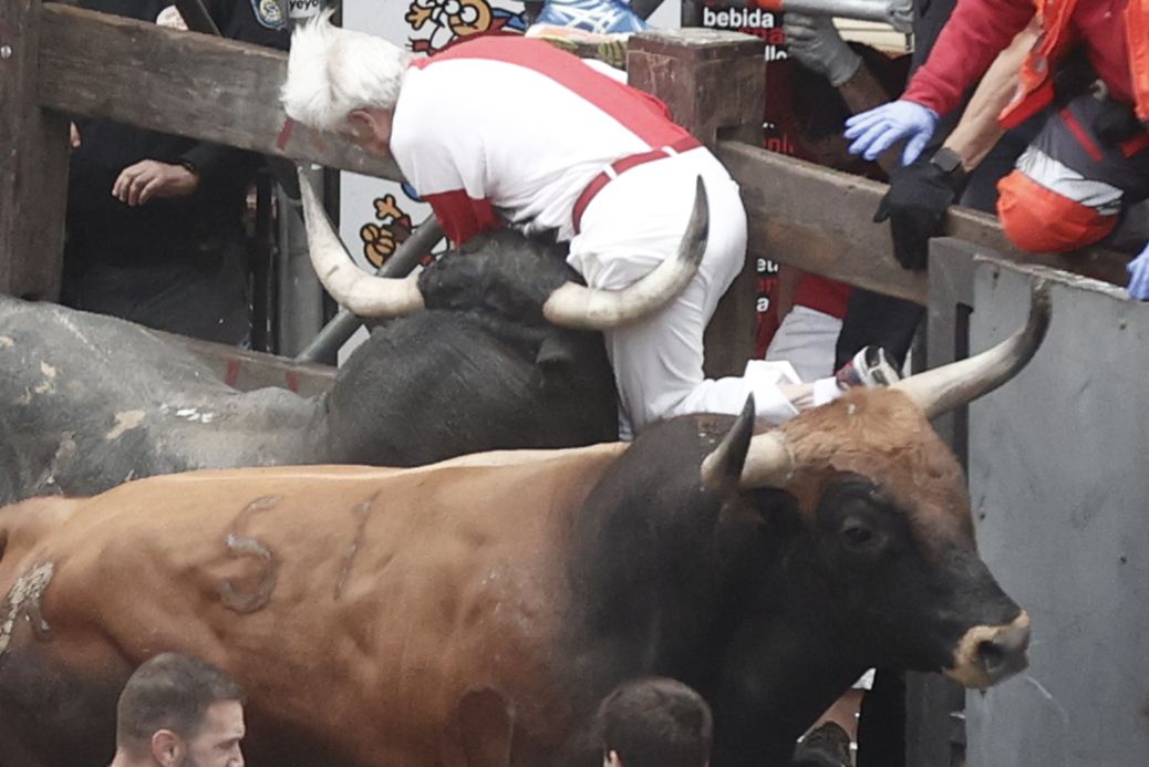 Mercaderes eta Estafeta arteko bihurgunean, zezen batek ezkerrean harrapatuta geratu den gizon bat harrapatu eta lurretik altxatu du. Ez dio adarkadarik eman, baina. JESUS DIFES / EFE