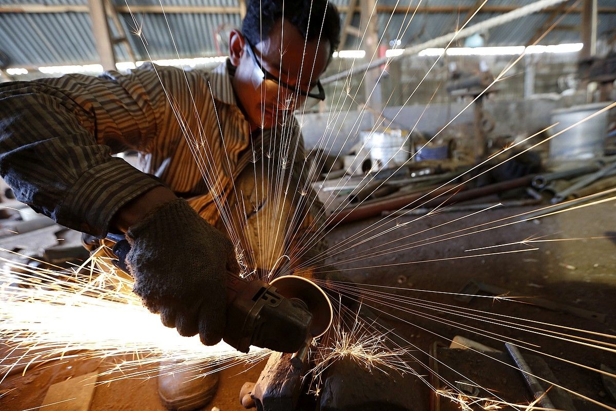 Behargin bat, metala mozten, babes eskasarekin, Indonesiako lantegi batean. HOTLI SIMANJUNTAK / EFE.