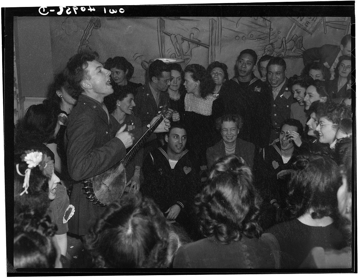 Pete Seeger, 1944an, sindikatu baten egoitzaren inaugurazioan kantari, Washingtonen. Eleanor Roosevelt ageri da argazki erdi-erdian, eserita. FSA / OWI.
