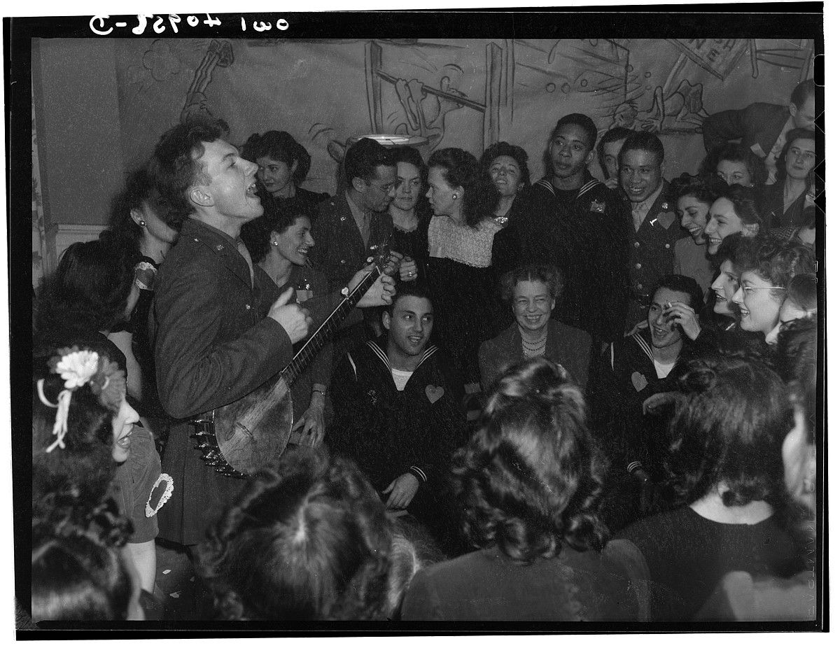 Pete Seeger, 1944an, sindikatu baten egoitzaren inaugurazioan kantari, Washingtonen. Eleanor Roosevelt ageri da argazki erdi-erdian, eserita. FSA / OWI. Pete Seeger, 1944an, sindikatu baten egoitzaren inaugurazioan kantari, Washingtonen. Eleanor Roosevelt ageri da argazki erdi-erdian, eserita. FSA / OWI.