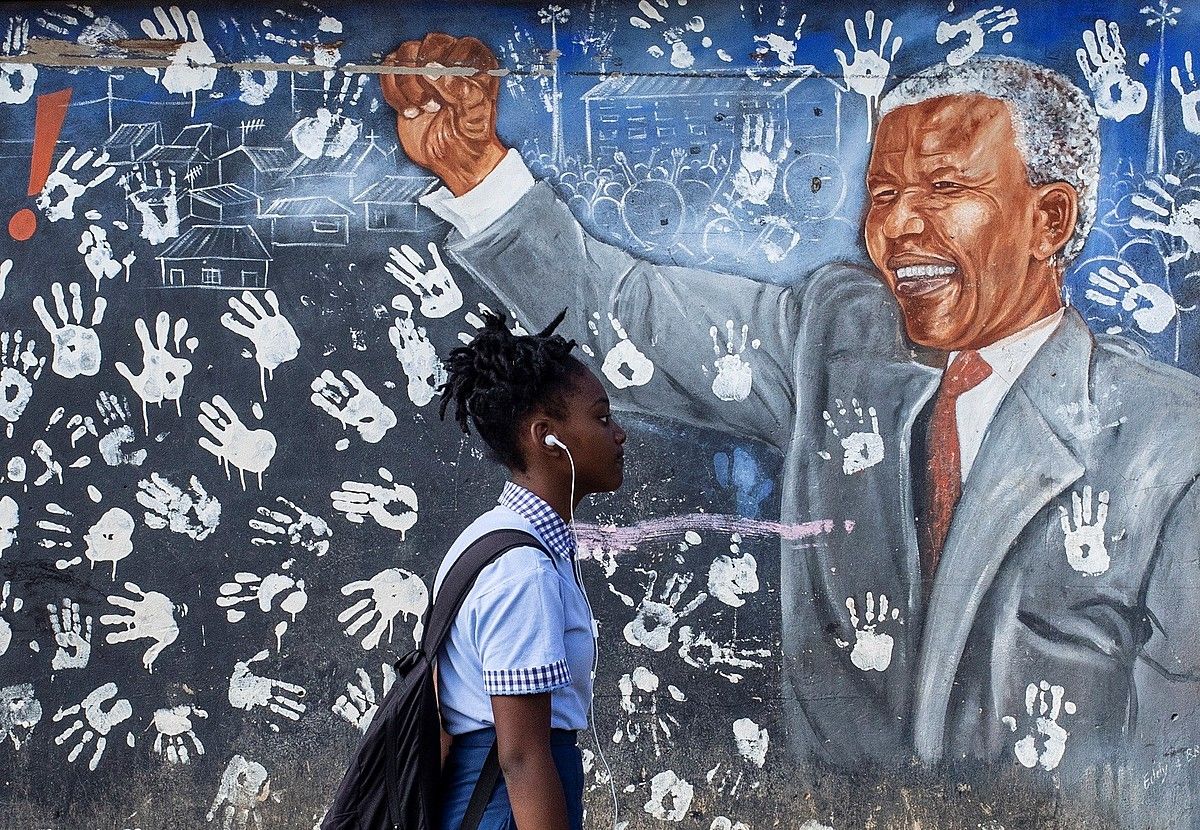 Ikasle bat atzo, Nelson Mandelaren mural baten aurretik pasatzen, Johannesburgon. KIM LUDBROOK / EFE.