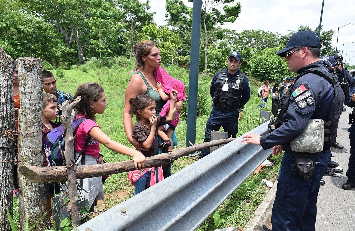 Erdialdeko Amerikako etorkin familia bateko kideak Mexikoko poliziekin hizketan, joan den ostegunean, Tapachula inguruan (Mexiko). JOSE TORRES / EFE.