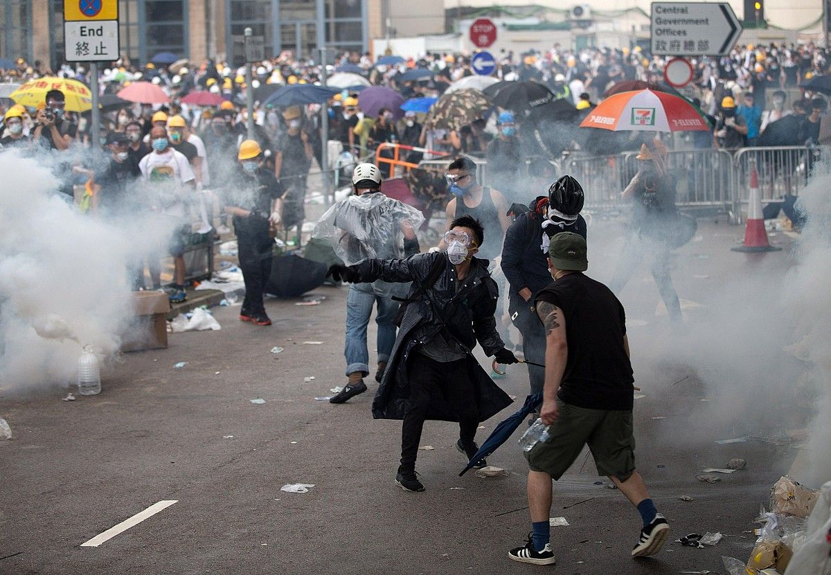 Kaskoekin, maskarekin eta aterkiekin babestu ziren hainbat manifestari, atzoko protestatan. JEROME FAVRE / EFE.