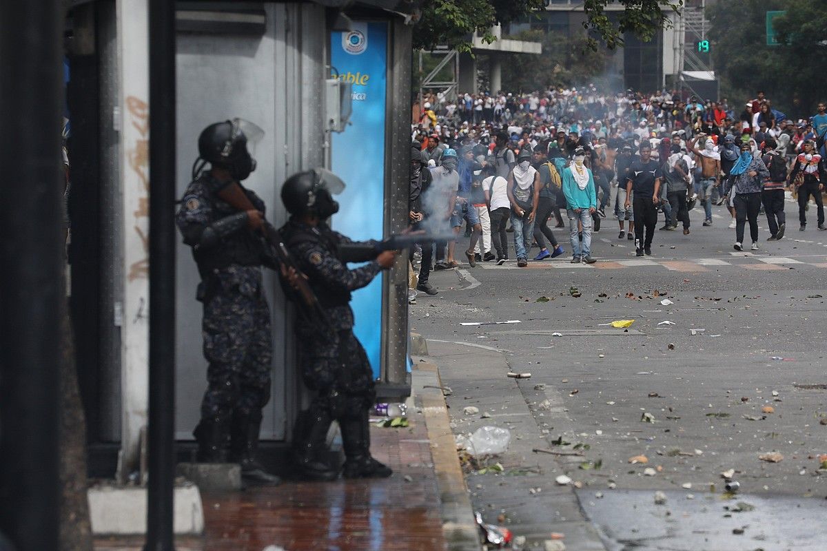 Oposizioaren jarraitzaileak eta Venezuelako segurtasun indarretako kideak borrokan, Caracasen, joan den urtarrilaren 23an. MIGUEL GUTIERREZ / EFE.