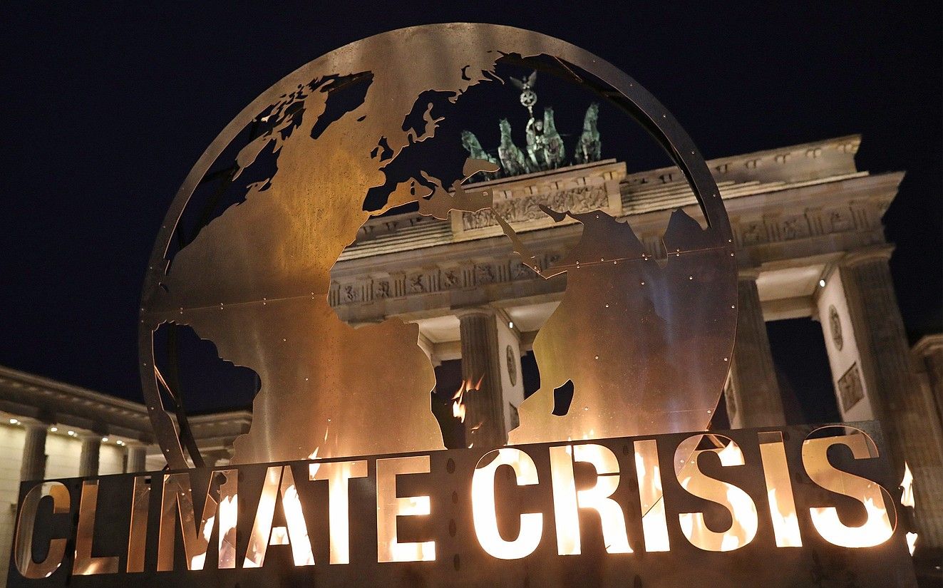 Greenpeace talde ekologistaren protesta bat, Berlinen, Brandenburgoko atean, klima krisiaz ohartarazteko. FOCKE STRANGMANN / EFE.