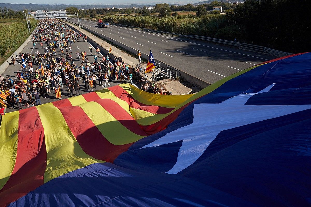 AP-7a. Girona eta Bartzelona lotzen dituen errepidea Askatasunaren Aldeko Martxak hartu zuen atzo. Estelada erraldoi bat zintzilikatu zuten zubi batetik. DAVID BORRAT / EFE.