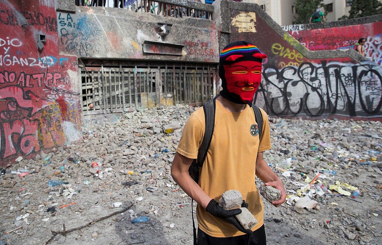 Manifestari bat eskuan armadari botatzeko harriak dituela, iragan astelehenean, Santiagon. ORLANDO BARRIA / EFE. Manifestari bat eskuan armadari botatzeko harriak dituela, iragan astelehenean, Santiagon. ORLANDO BARRIA / EFE.