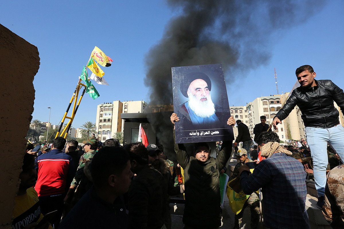 Herri Mobilizaziorako Indarrak talde xiitako kideak, AEBetako enbaxadaren kontrako protestetan, Bagdaden. Sayyid Ali Husseini Sistani Irakeko buruzagi xiitaren irudia du batek eskuetan. AHMED JALIL / EFE. Herri Mobilizaziorako Indarrak talde xiitako kideak, AEBetako enbaxadaren kontrako protestetan, Bagdaden. Sayyid Ali Husseini Sistani Irakeko buruzagi xiitaren irudia du batek eskuetan. AHMED JALIL / EFE.