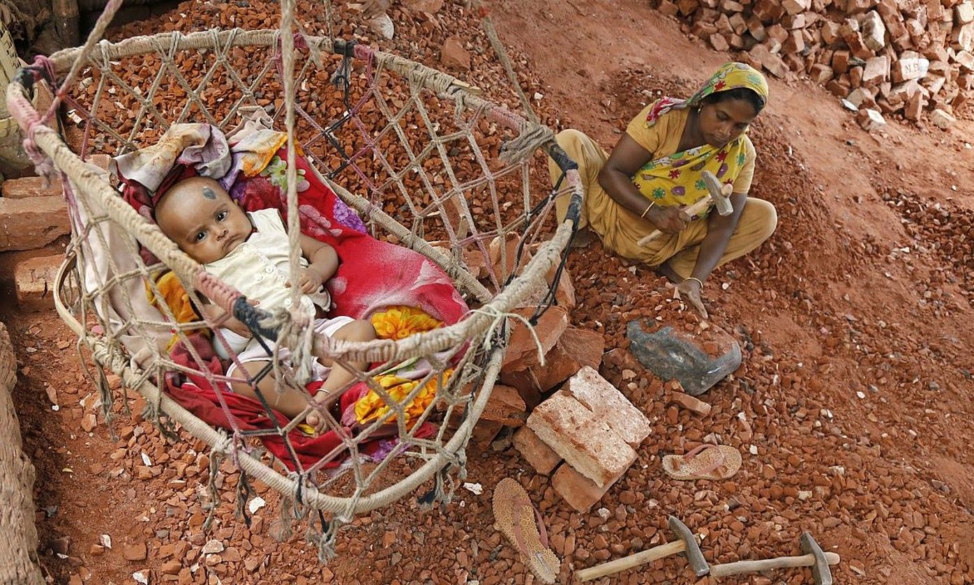 Emakume bat adreilu fabrika batean lanean, haurra zaintzen ari dela, Bangladeshen. ABIR ABDULLAH / EFE.