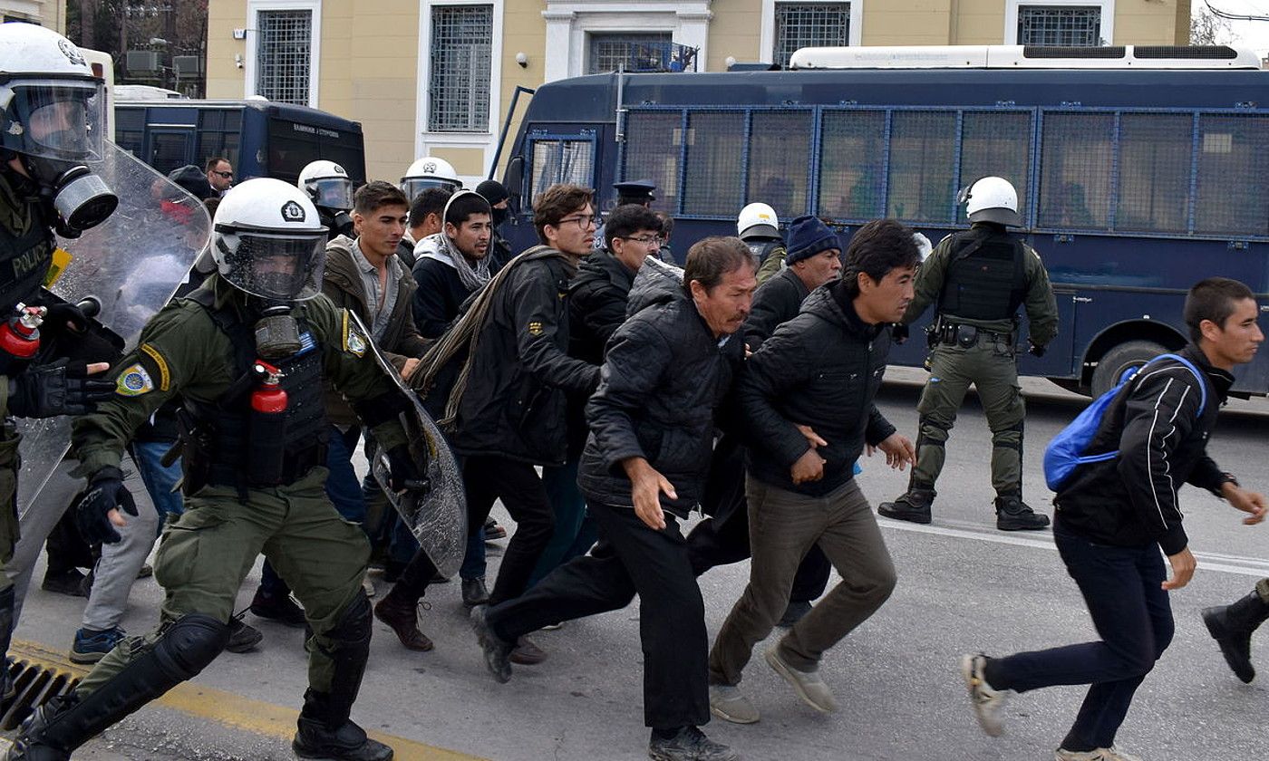 Migratzaileak protesan atzo Morian (Grezia), eta polizia haien atzetik. EFE.