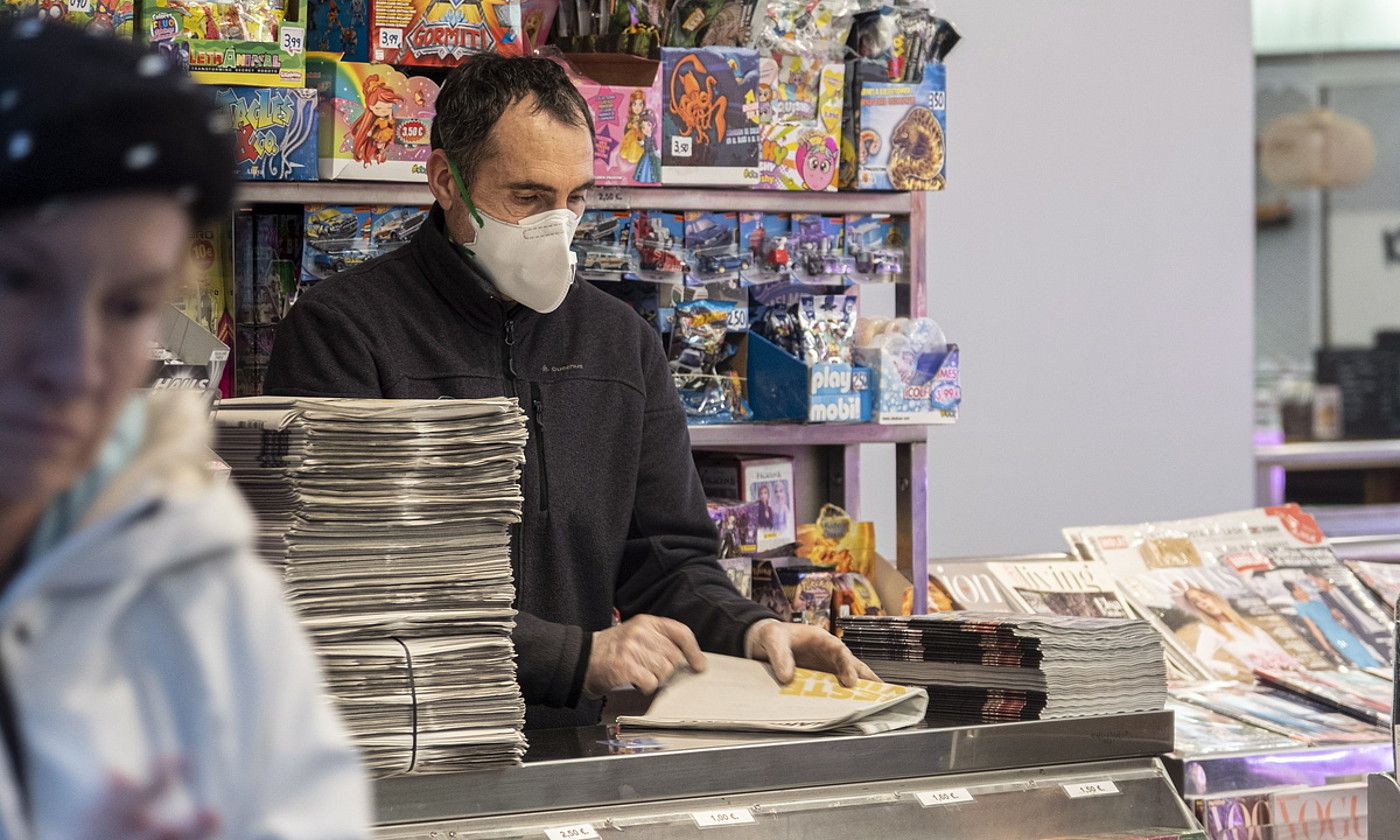 Saltzaile bat, maskara jarria duela, Donostiako San Martin merkataritza guneko kioskoan. JON URBE / FOKU.